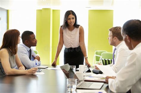 Female Boss Stands Addressing Team At Informal Work Meeting Stock Photo