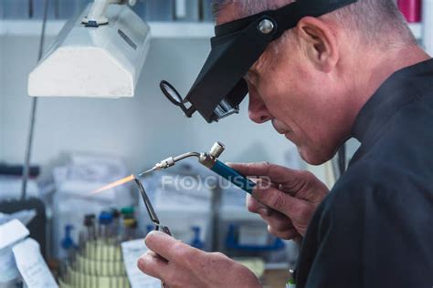 Male Jewelry Craftsman Using Miniature Blowtorch On Platinum Ring