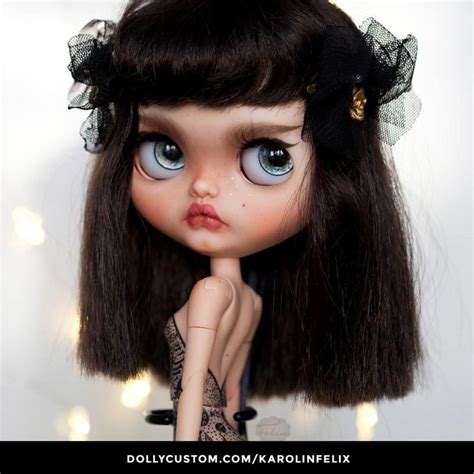A Close Up Of A Doll With Blue Eyes And Brown Hair Wearing A Black Dress