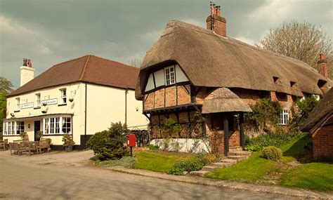 A Pretty Thatched Cottage And The Crown And Anchor Pub In The Village