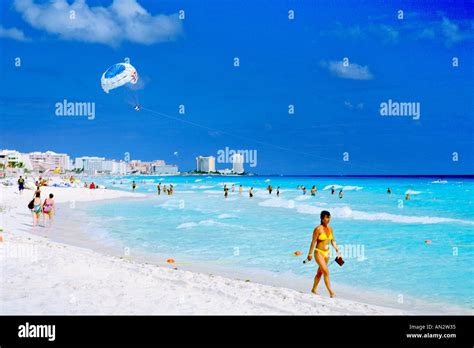 a woman in a yellow bikini strolls along the cancun beachfront on the caribbean coast of mexico