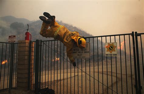 A Cal Fire Firefighter Hops Over A Locked Gate While Working The Tick