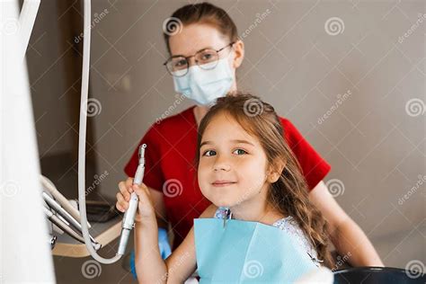 Cheerful Girl Child Holding Dental Drill And Smiling In Dentistry The