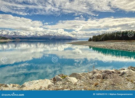 Panoramic View Of The Mountains And Lakeside Pine Trees Reflecting The