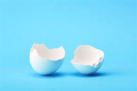 One White Broken Egg Shell On Blue Background Stock Photo