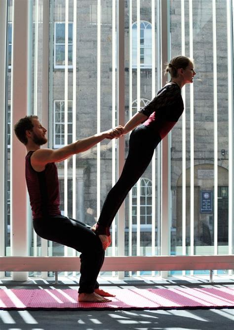 A Man And Woman Are Doing Yoga In Front Of Large Windows With Their