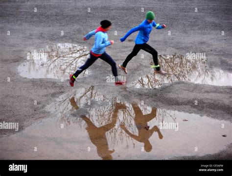 2 Young Women Running In Winter Jumping Over Wet Spots On The Way