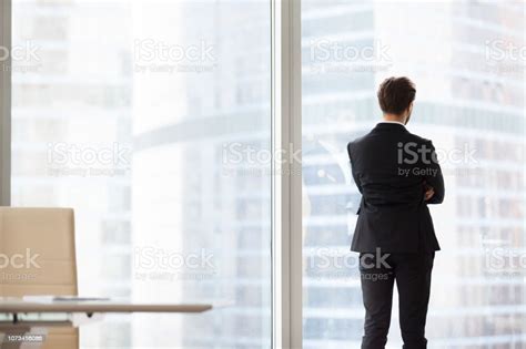 Back View Portrait Of Successful Businessman Standing By Window Stock