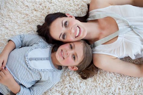 mãe feliz que empurra a menina com as flores que sentam se no carrinho de mão foto de stock