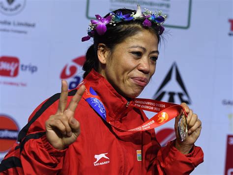 A Woman In A Red Jacket Is Holding Up Her Medal And Giving The Peace Sign