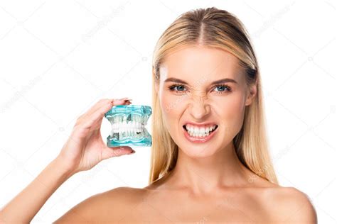 mujer desnuda mostrando dientes y sosteniendo modelo de mandíbula aislado en blanco