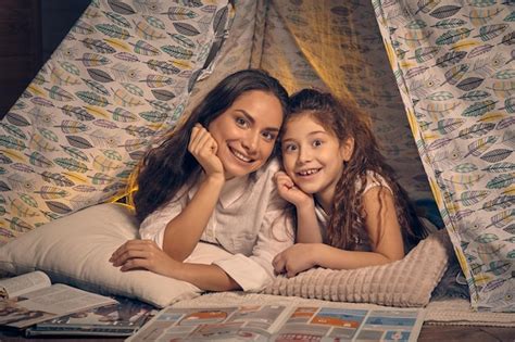 Premium Photo Mother And Daughter Are Sitting In A Teepee Tent With Some Pillows And Reading