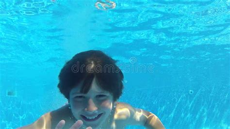 Boy Jumps Into Swimming Pool Then Swims Underwater To Camera Stock