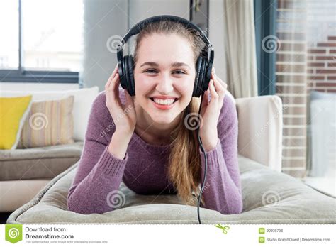 Cheerful Girl With Headphones Lying Down Enjoying Listening To Music