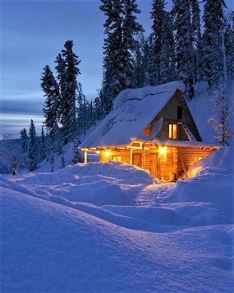 A Cabin Is Lit Up In The Snow At Night