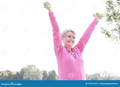 Happy Senior Woman Exercising With Dumbbells In Park Stock Image