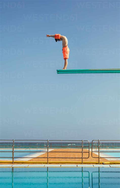 Boy Stands On A Diving Platform About To Dive Into The Swimming Pool