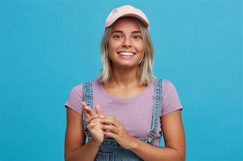 Free Photo Cute Blonde Female Wears Denim Overalls Casual T Shirt Smiles And Shows Her