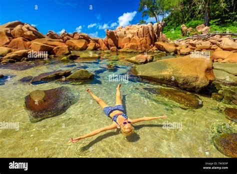 La Digue Anse Caiman Natural Pool Blonde Young Woman In Bikini Sunbathing On Crystal Water Of