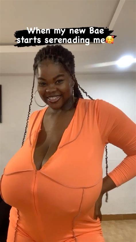 A Woman In An Orange Top Smiling At The Camera With Her Hands On Her Hips