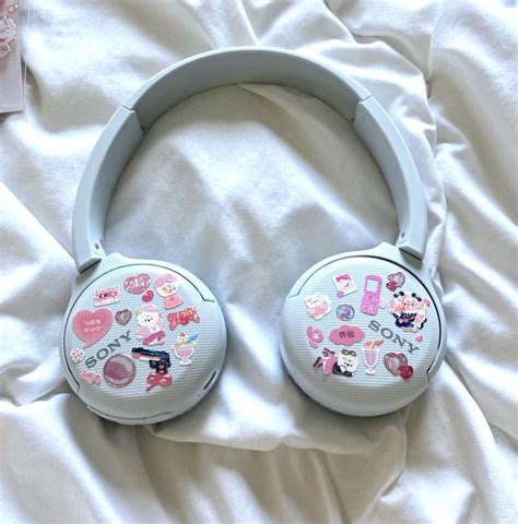 A Pair Of Headphones Sitting On Top Of A White Bed Covered In Pink Stickers