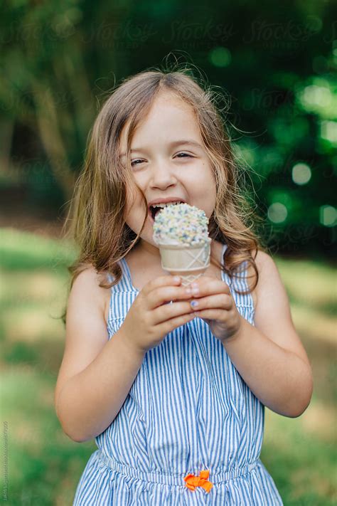 Cute And Happy Young Girl Eating Ice Cream Outside By Jakob Lagerstedt