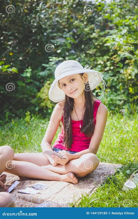 Beautiful Girl 10 Years Old In A White Hat Sitting On The Grass In The Summer Garden Stock Image
