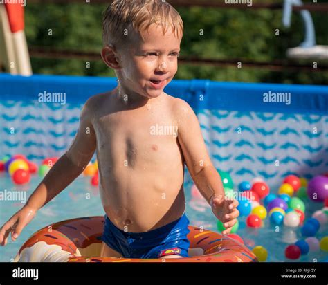 Happy Kid Boy Playing With Colorful Inflatable Ring In Outdoor Swimming