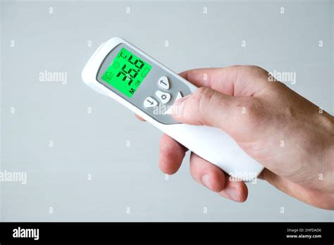 Hand Holding Contactless Thermometer Showing Temperature 366 Degrees