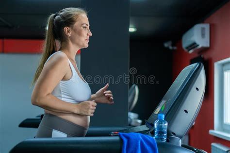 Smiling Pregnant Woman Running On A Treadmill The Concept Of A Healthy