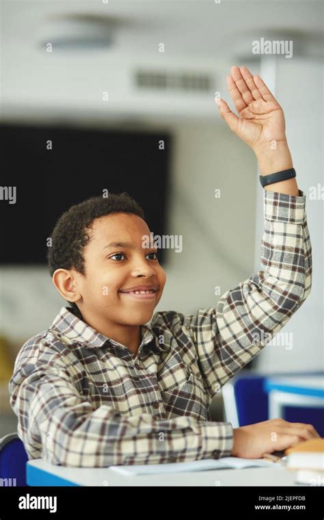 Vertical Portrait Of Young Black Boy Raising Hand In Class And Smiling