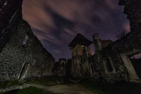 Ruins Of Medieval Castle At Night With Amazing Starry Sky And Clouds