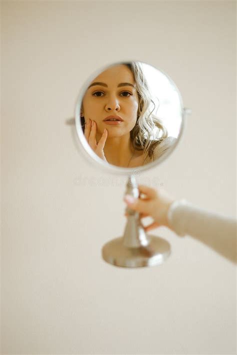 Young Caucasian Woman Looks In The Mirror And Fixes Her Makeup The