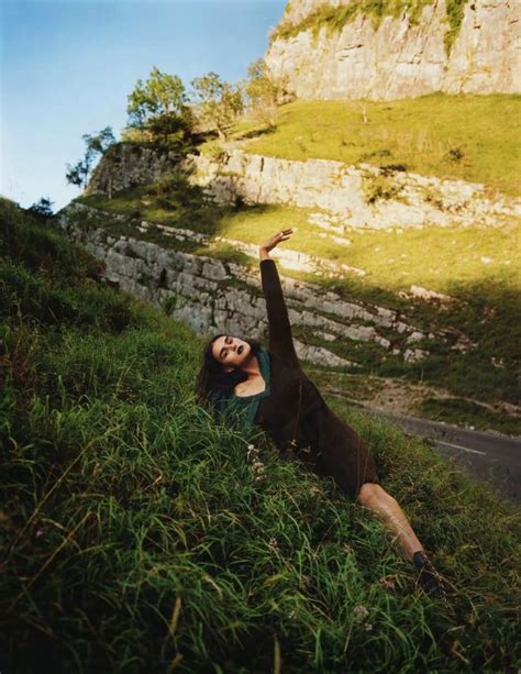 A Woman Is Laying Down In The Grass And Reaching Up Into The Air With