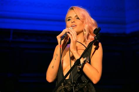 a woman with pink hair is singing into a microphone