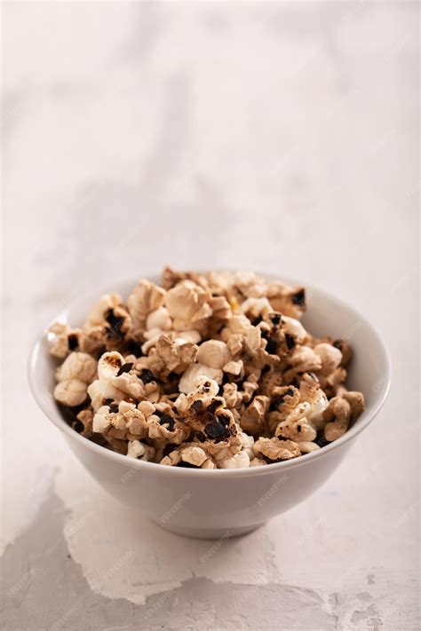 Premium Photo | Burnt popcorn in the small white bowl on ceramic