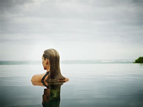 Woman Standing In Infinity Pool By Thomas Barwick