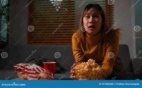 jovem animada comendo pipoca e assistindo filme na sala de estar conceito de hobby de