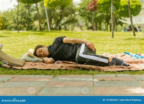 Young Man In Black Clothings Sleeping On Grasses In A Public Park