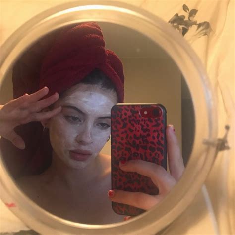 A Woman With A Towel On Her Head Is Looking At Her Cell Phone In The Mirror