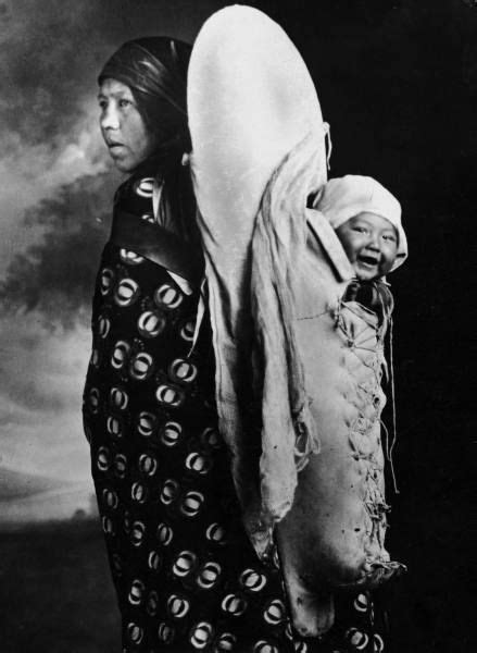 A Native American Mother And Her Baby Happily Hanging On Her Back From