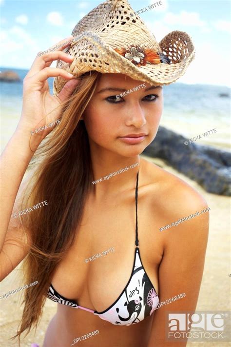 A Young Woman Wearing A Bikini And A Sunhat On Anini Beach Kauai Hawaii United States Of