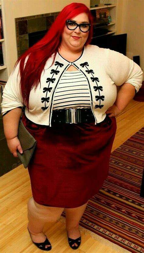 a woman with red hair and glasses is standing in a living room wearing a skirt