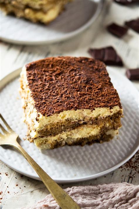 A Close Up Shot Of A Square Of Easy Tiramisu On A White Plate With A Gold Fork Authentic
