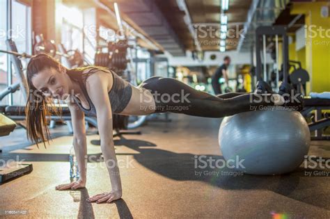 Young Woman Doing Pushups With Medicine Ball In Gym Stock Photo