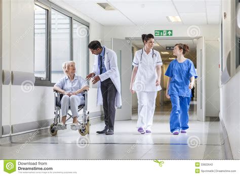 Doctors Nurse Senior Female Patient In Hospital Corridor Stock Photo