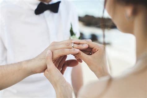 le marié met une bague au doigt de la mariée pendant la cérémonie de mariage photo premium