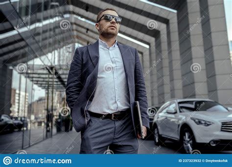 Young Businessman In Sunglasses Holding His Laptop Walking On The