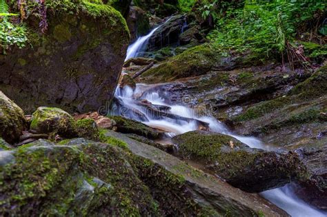 Long Exposure Shot Of A Small River Cascade Flowing Down Mossy Rocks