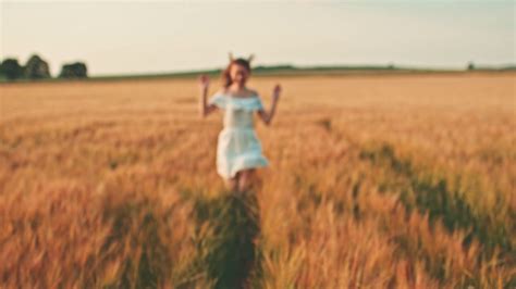 Beautiful girl running on sunlit wheat field. Slow motion ...